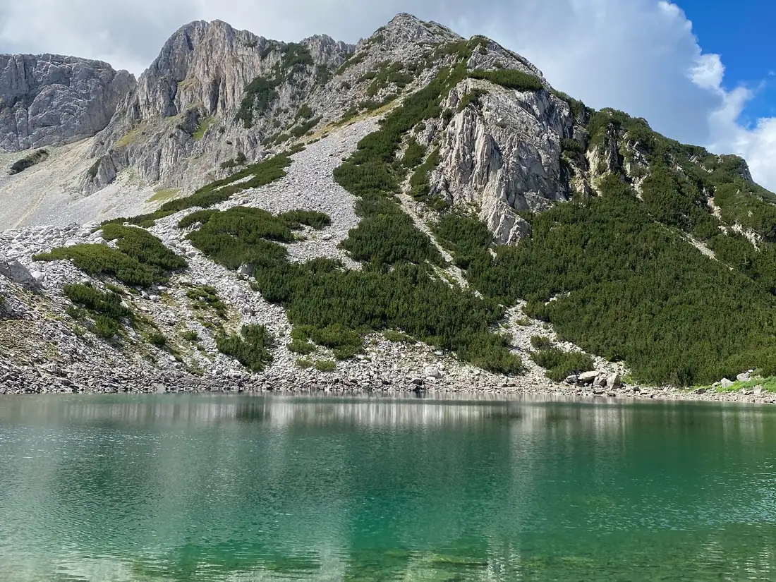 A rocky peak of the Pirin mountains reflected in a clear green lake